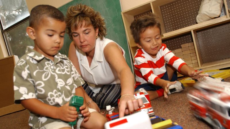 Image of woman helping two children play